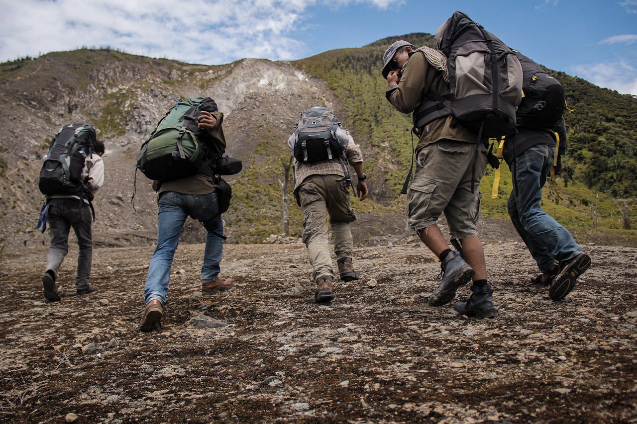 Five hikers with backpacks trekking up a mountain path in West Sumatra, Indonesia.